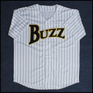 Puede incluir: Jersey de béisbol blanco con rayas verticales negras y la palabra "Buzz" en letras amarillas con contorno negro en la parte delantera.