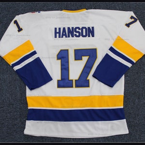 May include: White hockey jersey with blue and gold stripes. The number 17 is on the back with the name "HANSON" above it. The number 1 is on both sleeves.