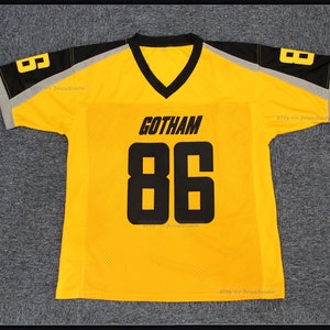 May include: Yellow football jersey with black and grey trim. The jersey has the word "GOTHAM" and the number "86" printed on the front.
