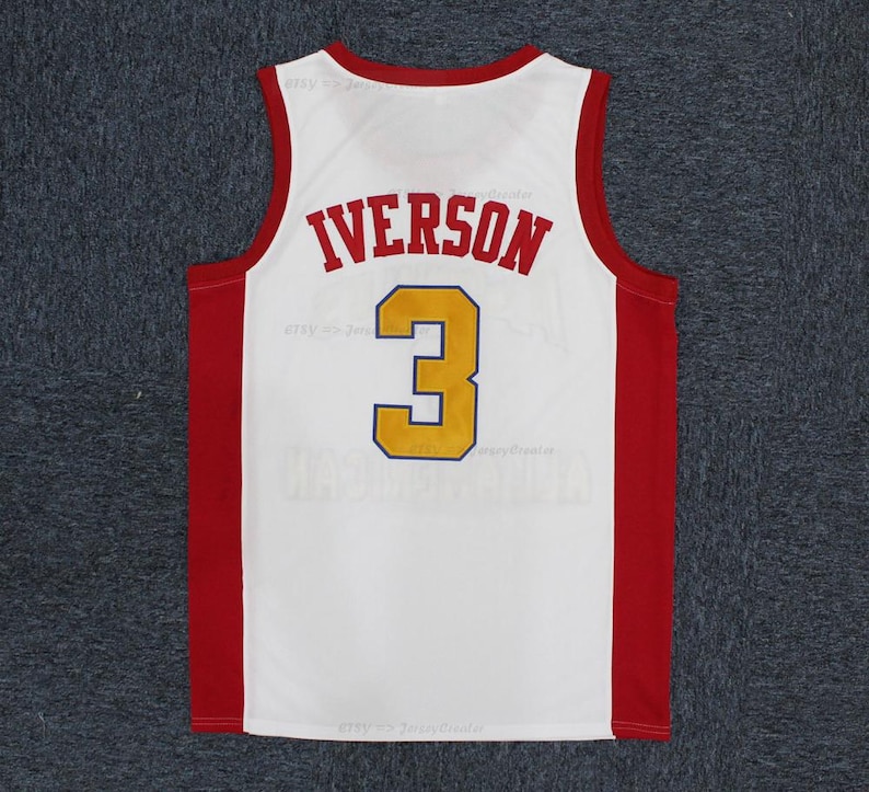May include: White basketball jersey with red and gold accents. The jersey features the name "IVERSON" in red block letters above the number "3" in gold with a navy blue outline. The jersey has red side panels and trim.