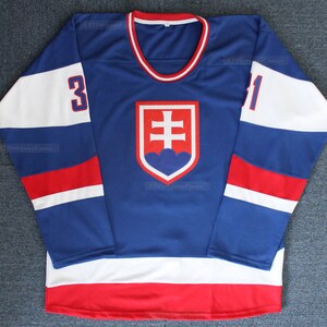 Könnte beinhalten: Ein blaues Hockeytrikot mit weißen und roten Streifen. Das Trikot trägt das slowakische Staatswappen auf der Vorderseite und die Nummer "31" auf dem rechten Ärmel.