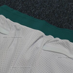 Puede incluir: Pantalones cortos de malla blancos con cintura verde. Los pantalones cortos tienen un cord&oacute;n blanco y una peque&ntilde;a etiqueta dorada. La tela est&aacute; perforada con peque&ntilde;os agujeros.