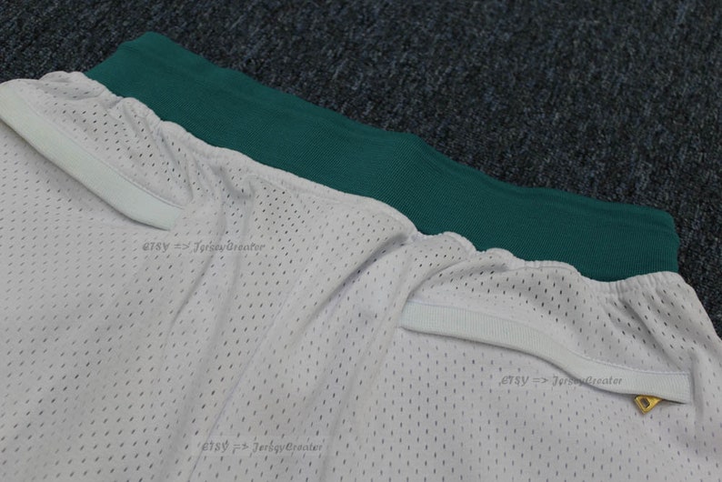Puede incluir: Pantalones cortos de malla blancos con cintura verde. Los pantalones cortos tienen un cord&oacute;n blanco y una peque&ntilde;a etiqueta dorada. La tela est&aacute; perforada con peque&ntilde;os agujeros.