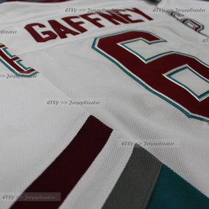 May include: White hockey jersey with maroon and teal accents. The number "6" and the name "GAFFNEY" are printed on the front of the jersey in maroon.