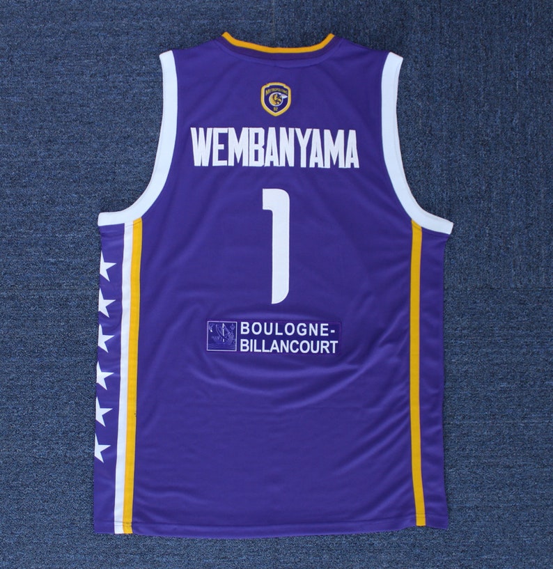 May include: Purple basketball jersey with white and yellow accents. The back of the jersey has the name "Wembanyama" and the number "1" in white. The text "BOULOGNE-BILLANCOURT" is printed below the number.