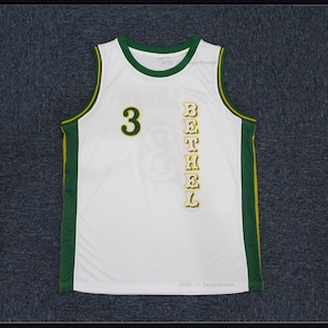 May include: White basketball jersey with green and yellow trim. The number "3" is on the front of the jersey, and the word "BETHEL" is vertically down the right side of the jersey.
