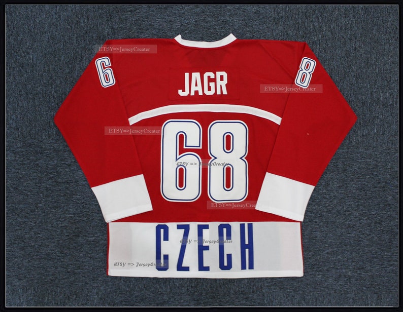 Peut inclure: Un maillot de hockey rouge avec des d&eacute;tails blancs et bleus. Le maillot affiche le nom "JAGR" au-dessus du num&eacute;ro "68" en blanc, avec le mot "CZECH" en bas. Le num&eacute;ro "6" est sur la manche gauche et "8" sur la droite.