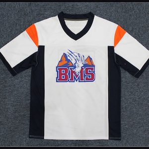 Può includere: Maglia a maniche corte bianca, blu e arancione con un logo di montagna e capra. Il logo dice "BMS".