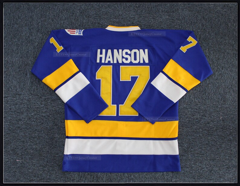 May include: A blue hockey jersey with yellow and white stripes. The number "17" and the name "HANSON" are on the back of the jersey.