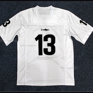 K&ouml;nnte beinhalten: Wei&szlig;es Football-Trikot mit schwarzer Nummer 13 und einem Hai-Logo. Das Trikot hat ein Mesh-Gewebe und ist in Gr&ouml;&szlig;e L.