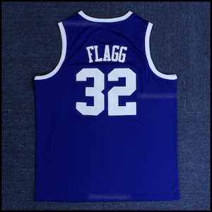 May include: A royal blue basketball jersey with white trim. The back of the jersey has the name "FLAGG" and the number "32" in white.
