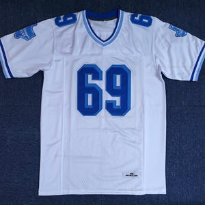 May include: White football jersey with blue accents and the number 69 in bold blue. The jersey has a V-neck collar and blue stripes on the sleeves. The text "CHAMPS 2019" is on the left sleeve.