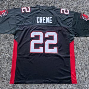 Könnte beinhalten: Schwarzes und graues Football-Trikot mit der Nummer 22 in Weiß und Rot. Das Wort "CREWE" steht auf der oberen Rückseite. Rote Akzente verlaufen an den Seiten. Teamlogo-Patches auf den Ärmeln.