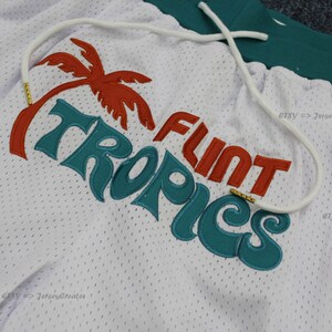 Puede incluir: Shorts de malla blancos con cord&oacute;n y dise&ntilde;o bordado en verde azulado y naranja. El dise&ntilde;o incluye una palmera y las palabras "FLINT TROPICS". Los shorts tienen una cintura verde.