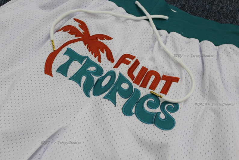 Puede incluir: Shorts de malla blancos con cord&oacute;n y dise&ntilde;o bordado en verde azulado y naranja. El dise&ntilde;o incluye una palmera y las palabras "FLINT TROPICS". Los shorts tienen una cintura verde.