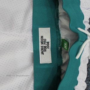 Puede incluir: Primer plano de pantalones cortos deportivos con tejido de malla blanca y cintura verde azulado. Una etiqueta dice "JACKIE MOON SEMI PRO 2008". Los pantalones cortos tienen un cord&oacute;n y una etiqueta XL.