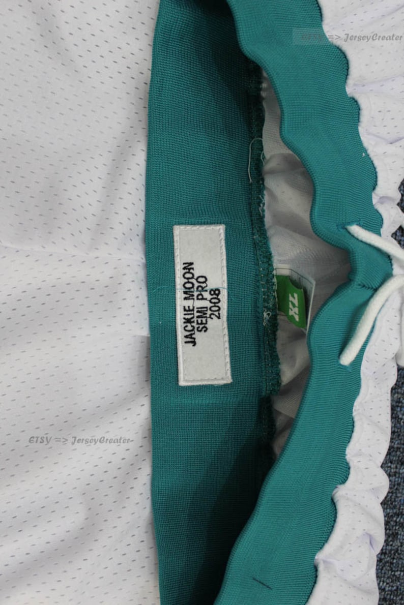 Puede incluir: Primer plano de pantalones cortos deportivos con tejido de malla blanca y cintura verde azulado. Una etiqueta dice "JACKIE MOON SEMI PRO 2008". Los pantalones cortos tienen un cord&oacute;n y una etiqueta XL.