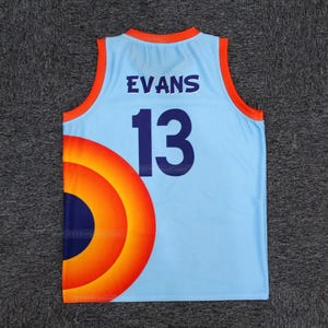 May include: Light blue basketball jersey with the name "EVANS" and the number "13" in navy blue. The jersey has orange and red accents and a large circular design on the lower left side.