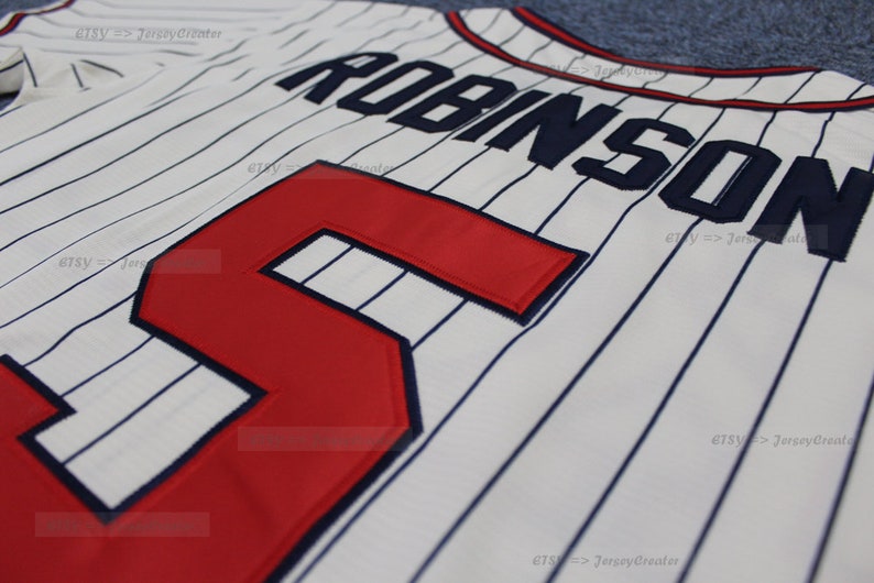 May include: White baseball jersey with blue pinstripes and red number "5" on the front. The name "ROBINSON" is sewn on the back in blue.