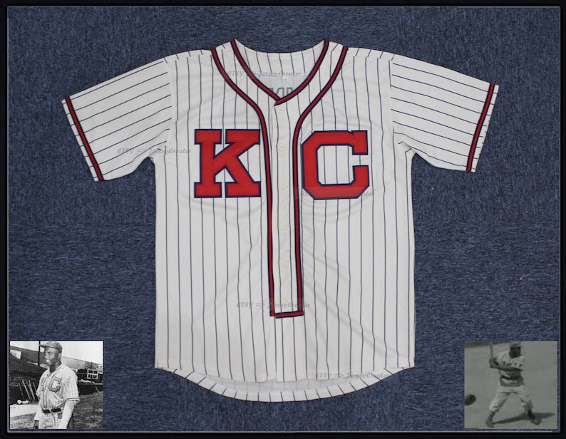 May include: White baseball jersey with blue and white stripes. The jersey has red lettering that says "KC".