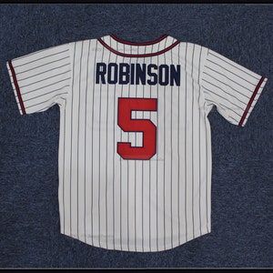 May include: White baseball jersey with blue pinstripes and red lettering. The back of the jersey has the name "ROBINSON" and the number "5" on it.