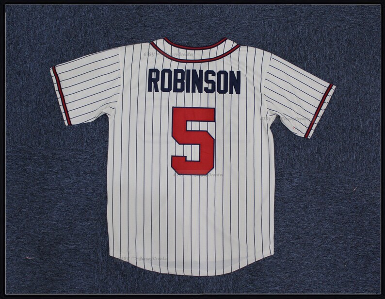 May include: White baseball jersey with blue pinstripes and red lettering. The back of the jersey has the name "ROBINSON" and the number "5" on it.