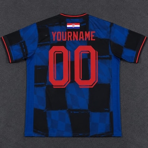 May include: A short-sleeved sports jersey featuring a blue and black checkered pattern. The back displays the red text YOURNAME above the red number 00. A small Croatian flag is positioned at the neckline, and the sleeves have thin red trim.