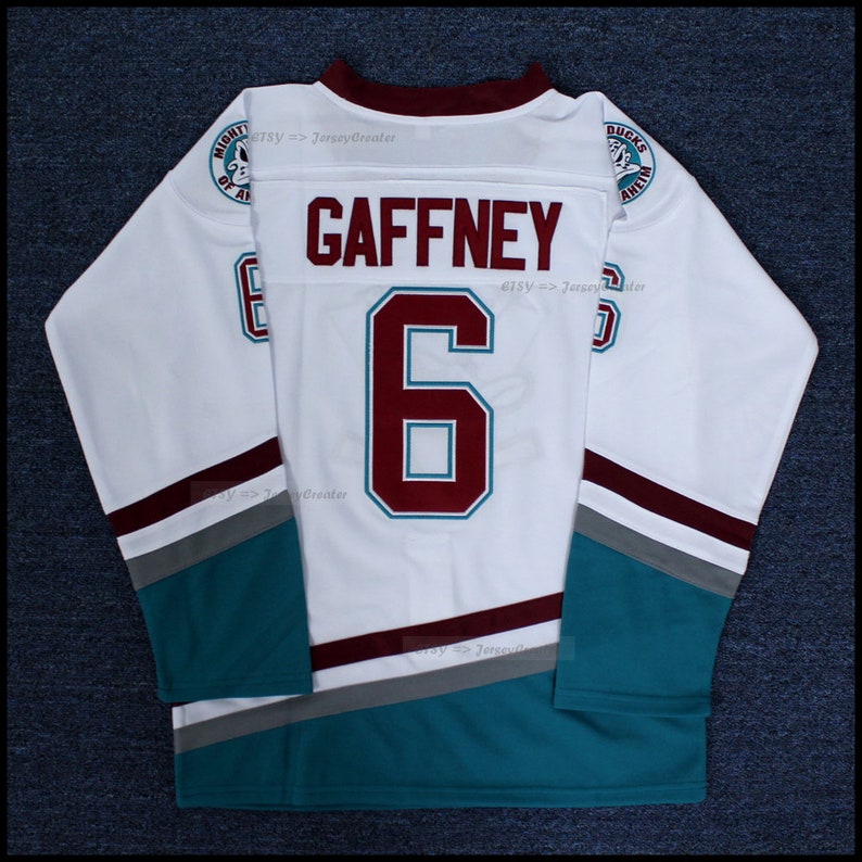 May include: White hockey jersey with maroon and teal accents. The back of the jersey has the number "6" and the name "GAFFNEY" in maroon lettering. The jersey has a Mighty Ducks of Anaheim logo on the left shoulder and a Ducks Anaheim logo on the right shoulder.