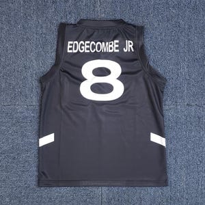 Może przedstawiać: Czarny podkoszulek sportowy z napisem "EDGECOMBE JR" i numerem "8" w kolorze białym. Podkoszulek ma białe akcenty po bokach. Podkoszulek jest bez rękawów i wykonany z błyszczącego materiału.