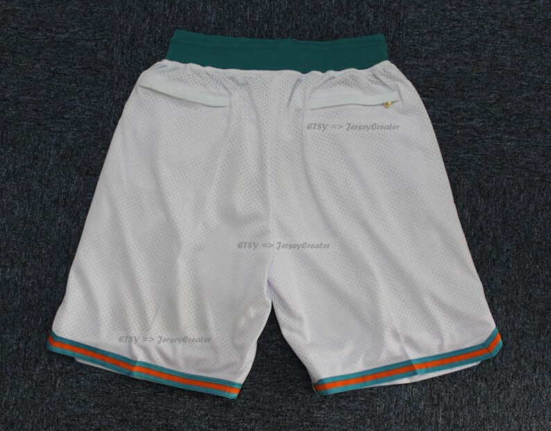 Puede incluir: Pantalones cortos deportivos de malla blanca con ribete turquesa y naranja. Los pantalones cortos tienen una cintura turquesa y dos bolsillos. El texto "Etsy => JerseyCreator" est&aacute; impreso en los pantalones cortos.