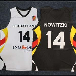 May include: Two basketball vests, one white and one black. The white vest has "DEUTSCHLAND" and the number "14" in black. The black vest has "NOWITZKI" and the number "14" in white. Both vests feature German flag colours.