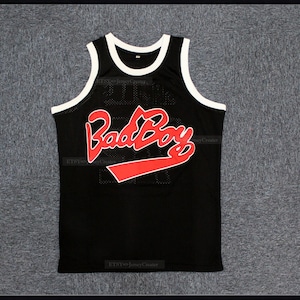 May include: Black basketball jersey with a red "Bad Boy" logo on the front. The jersey has a white trim around the neck and armholes.