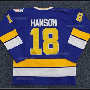 May include: A blue hockey jersey with white and yellow stripes. The number 18 and the name "HANSON" are on the back of the jersey in yellow.