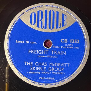 Può includere: Un disco in vinile vintage con etichetta blu e argento. L'etichetta "ORIOLE" presenta il titolo della canzone "FREIGHT TRAIN" di The Chas McDevitt Skiffle Group. Il disco suona a 78 giri e fu registrato nel 1957.