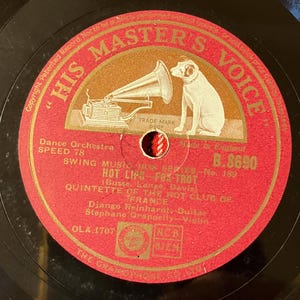 May include: A vintage 78 RPM phonograph record with a red and gold His Master's Voice label. The label features a dog listening to a gramophone, text reading Hot Lips - Fox Trot, and credits for the Quintette of the Hot Club of France.