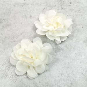 Könnte beinhalten: Zwei weiße Stoffblumen mit einer gekräuselten Textur. Die Blumen befinden sich auf einem grauen Hintergrund.