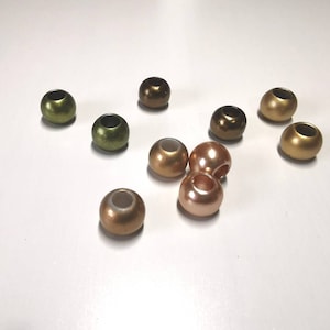 Könnte beinhalten: Sortiment runder Perlen in verschiedenen Gold-, Grün- und Brauntönen. Die Perlen haben eine glatte, glänzende Oberfläche.