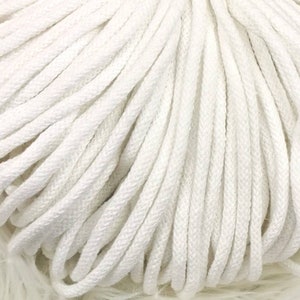 Könnte beinhalten: Nahaufnahme eines Knäuels aus weißer Makramee-Kordel. Die Kordel ist eng gewickelt und zeigt eine strukturierte Oberfläche. Die leuchtend weiße Farbe deutet auf ein sauberes und vielseitiges Material für verschiedene Bastelprojekte hin.