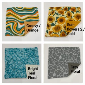 May include: Four square fabric swatches featuring distinct patterns: a wavy orange, teal, and white print; a yellow sunflower print; a teal floral print; and a gray floral print. Each swatch shows a solid-colored backing in orange, gold, cream, or gray.