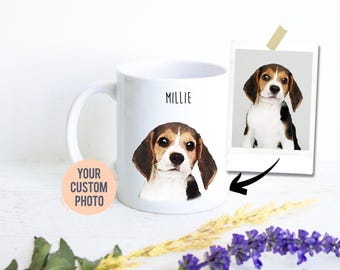 Może przedstawiać: Biały ceramiczny kubek z akwarelową ilustracją psa rasy beagle oraz nadrukowanym powyżej imieniem MILLIE. Obok kubka znajduje się kwadratowe zdjęcie tego samego beagle'a, z czarną strzałką wskazującą od zdjęcia w stronę kubka.