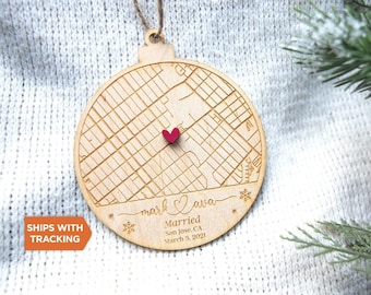 May include: A round wooden ornament featuring an engraved street map with a small red heart placed in the centre. The text reads mark and ava, Married, San Jose, CA, March 3, 2021, with snowflake accents and a twine loop for hanging.