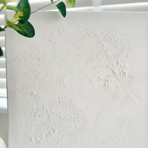 May include: White textured canvas board with a rough, uneven surface. The board is blank and ready for painting or other creative projects.