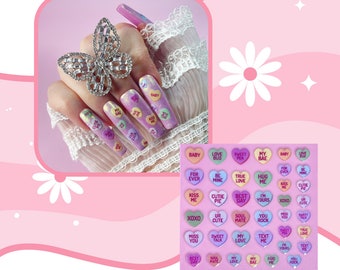 May include: A sheet of colourful heart-shaped stickers with various romantic phrases such as "Love Bug", "True Love", "Soul Mate", "Best Day", "My Bae", "You Rock", "Miss You", "Sweet Talk", "Cutie Pie", "Kiss Me", "XOXO", "I'm Yours", and "Baby".
