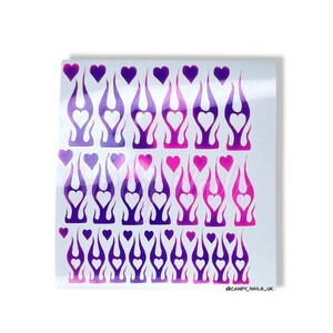 Puede incluir: Una hoja de pegatinas para u&ntilde;as con un patr&oacute;n repetido de llamas moradas y rosas con corazones blancos en su interior. Las pegatinas est&aacute;n sobre un fondo blanco. @CANDY_NAILS_UK