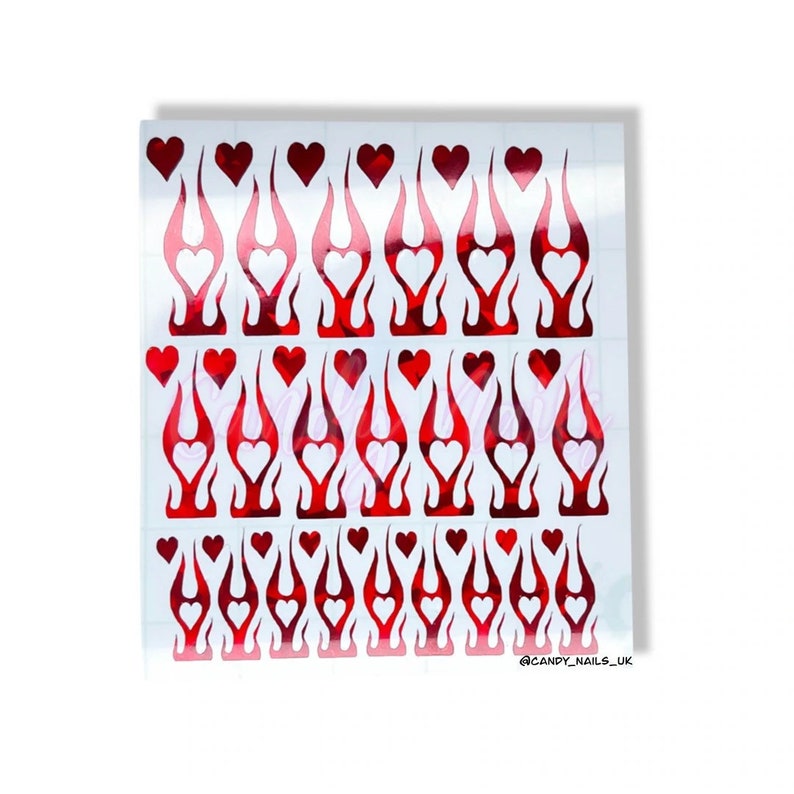 Puede incluir: Una hoja de pegatinas para u&ntilde;as rojas y blancas con un dise&ntilde;o de llama y un coraz&oacute;n en el centro de cada llama. La hoja contiene 36 pegatinas. @CANDY_NAILS_UK