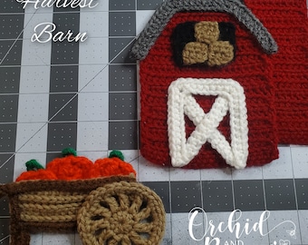 Puede incluir: Granero de cosecha tejido a crochet con techo rojo, puerta blanca y silo gris. Un carro marrón con calabazas naranjas está en primer plano. El texto "Harvest Barn" está escrito sobre el granero y "Orchid and Bees" está escrito debajo del carro.