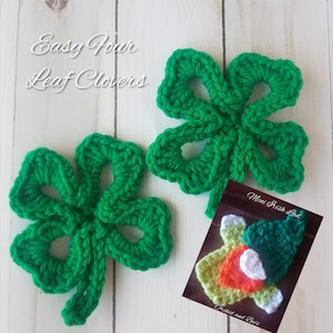 May include: Two green crocheted four-leaf clovers. The clovers are made with green yarn and have a simple design. The text "Easy Four Leaf Clovers" is at the top of the image. The text "Mini Irish Lad" is at the bottom of the image.
