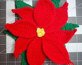 May include: A crocheted Christmas poinsettia with red petals and green leaves. The poinsettia is on a black and white grid background. The text "Christmas Poinsettia" is at the top of the image and "Orchid and Bee's" is at the bottom.