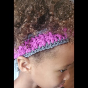 Puede incluir: Una diadema de crochet gris y rosa. La diadema está hecha con un punto sencillo y tiene un borde rosa.