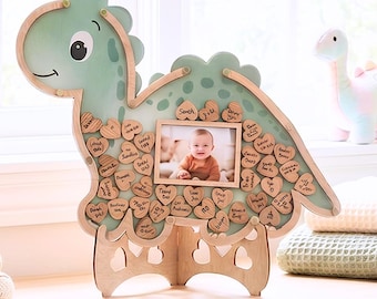 Puede incluir: Un marco de madera con forma de dinosaurio verde claro que presenta una ranura central rectangular para fotos y numerosos recortes de madera pequeños en forma de corazón adheridos a la superficie. Se sostiene sobre un soporte de madera a juego.